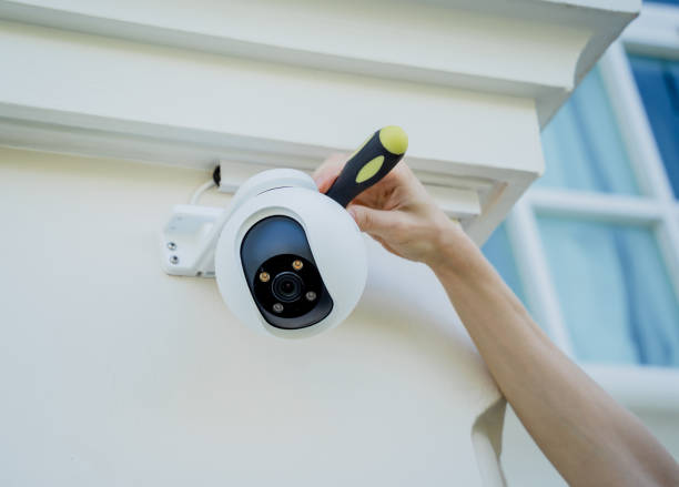A technician installs a CCTV camera on the facade of a residential building